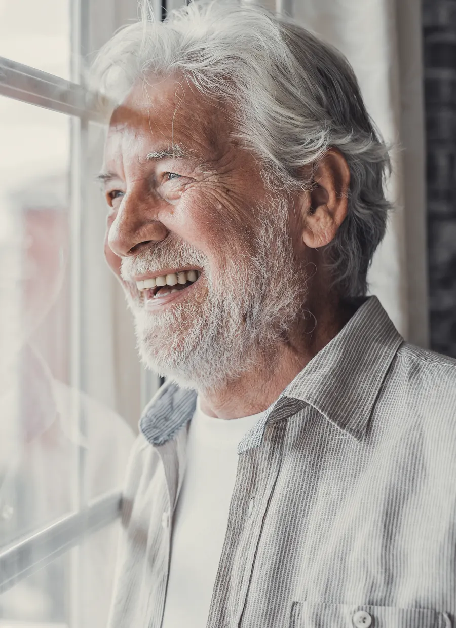 Hombre sonriendo junto a una ventana (imagen referencial)